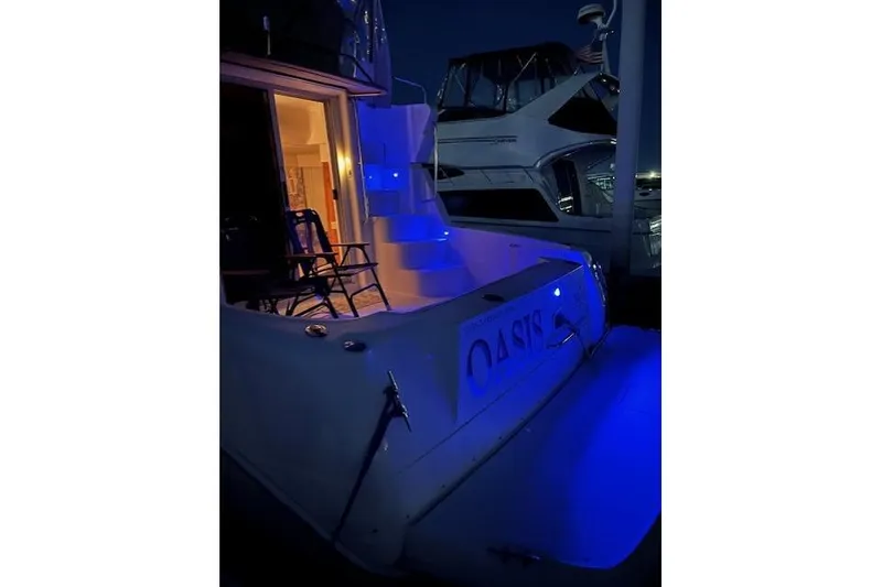 Slide: The Image of 1999 Silverton 351 Sedan yacht with blue lighting at night, featuring open cabin door. - 4
