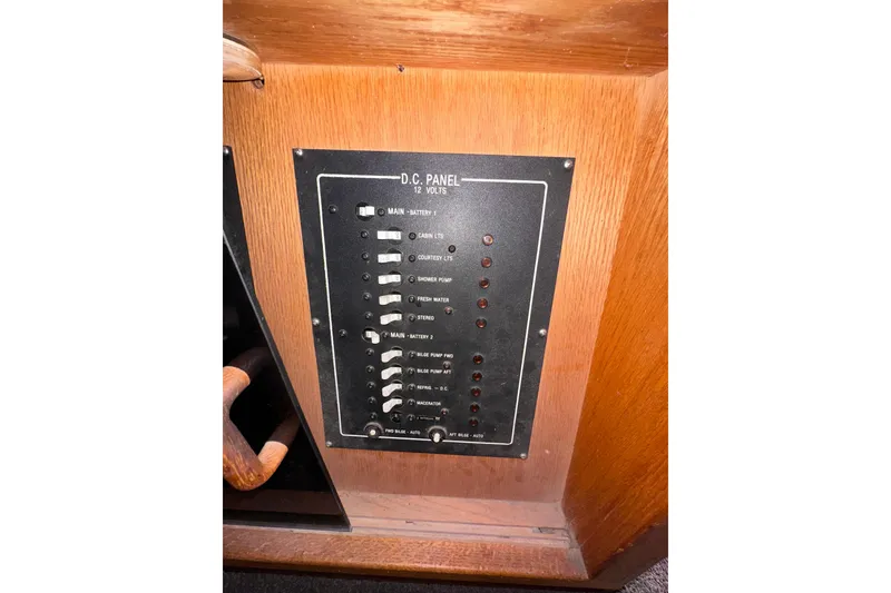 Slide: The Image of 1988 Silverton 37 Convertible DC panel with switches and indicators on wooden surface. - 49