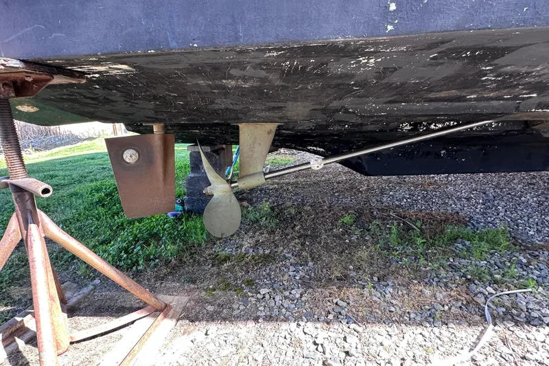 Slide: The Image of 1988 Silverton 37 Convertible boat underside showing propeller and rudder on dry land. - 53