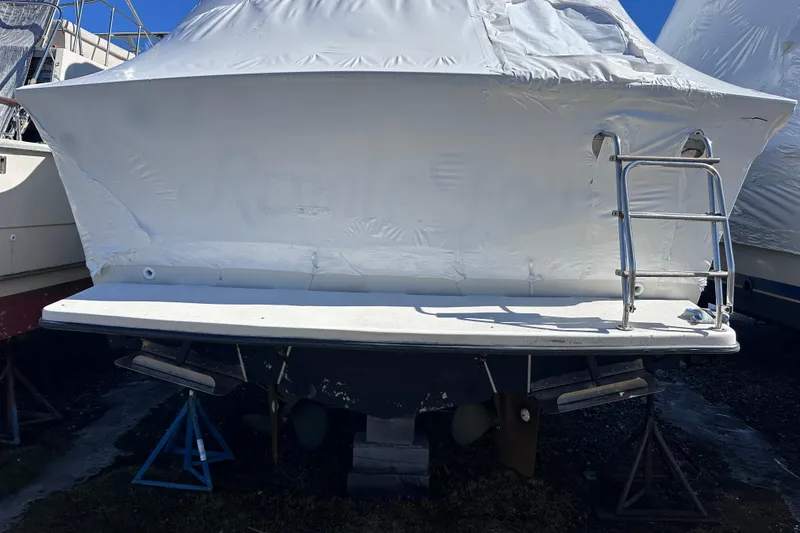 Slide: The Image of 1988 Silverton 37 Convertible boat, covered and elevated, with a metal ladder at the stern. - 8