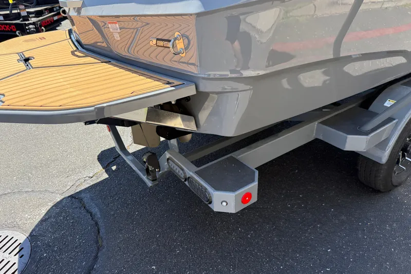 Slide: The Image of 2025 MasterCraft XT22 boat rear view with trailer, featuring teak swim platform. - 11