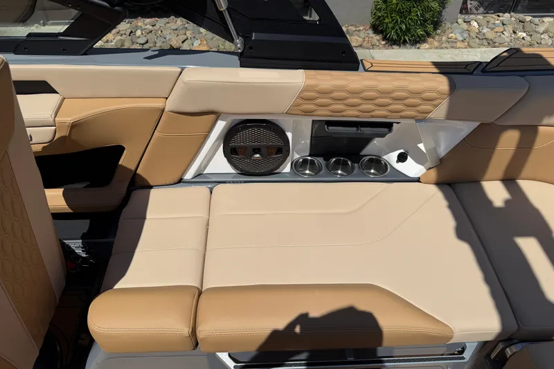 Slide: The Image of 2025 MasterCraft XT22 interior with tan leather seats, cup holders, and speaker system. - 19