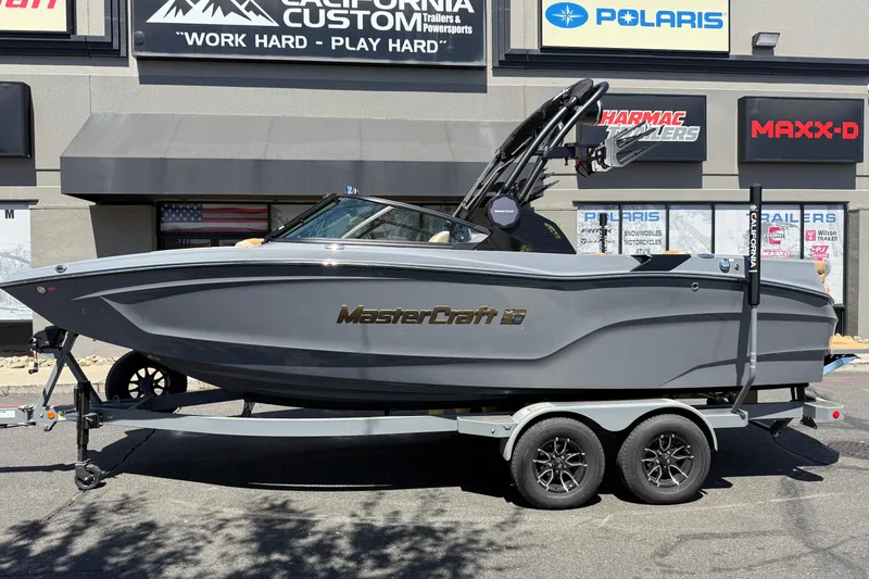 Slide: The Image of 2025 MasterCraft XT22 boat on trailer, parked outside dealership with signage. - 2