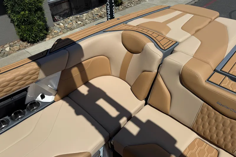Slide: The Image of 2025 MasterCraft XT22 boat interior with tan and beige seating, cup holders, and stylish design. - 20