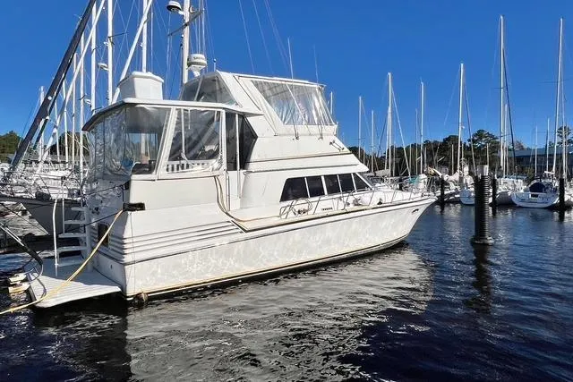 The Image of 1989 Trojan 12 Meter Motor Yacht docked in a marina under clear blue skies. - 0