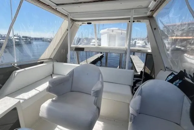 Slide: The Image of 1989 Trojan 12 Meter Motor Yacht interior with white seating and marina view. - 10