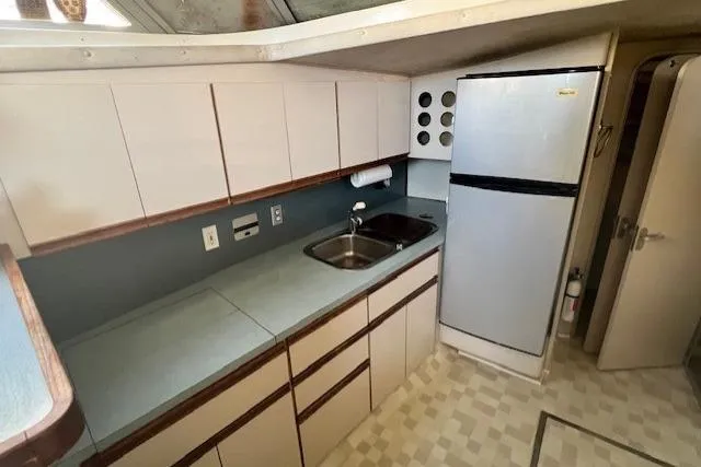 Slide: The Image of 1989 Trojan 12 Meter Motor Yacht kitchen with cabinets, sink, and refrigerator. - 17