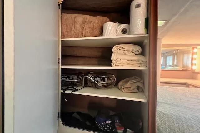 Slide: The Image of Cabinet storage inside a 1989 Trojan 12 Meter Motor Yacht, featuring towels and household items. - 21