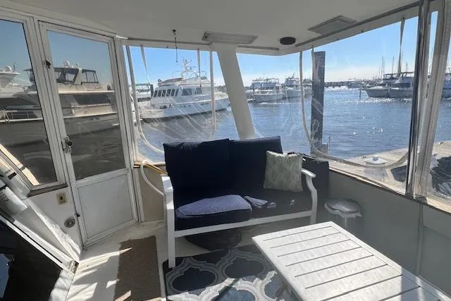 Slide: The Image of 1989 Trojan 12 Meter Motor Yacht interior with marina view, featuring seating and table. - 48