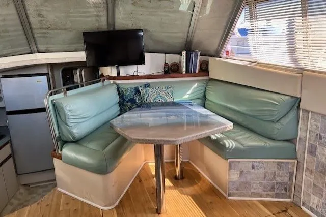 Slide: The Image of 1989 Trojan 12 Meter Motor Yacht interior with teal seating, dining table, and TV. - 50