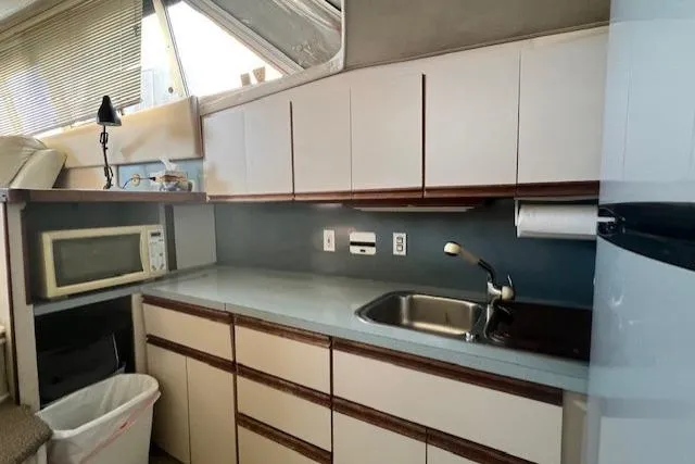 Slide: The Image of 1989 Trojan 12 Meter Motor Yacht kitchen with sink, microwave, and cabinets. - 54