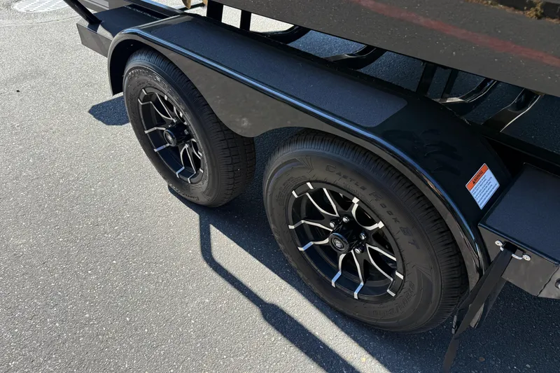 Slide: The Image of Trailer wheels of a 2026 MasterCraft NXT24 boat on pavement. - 11