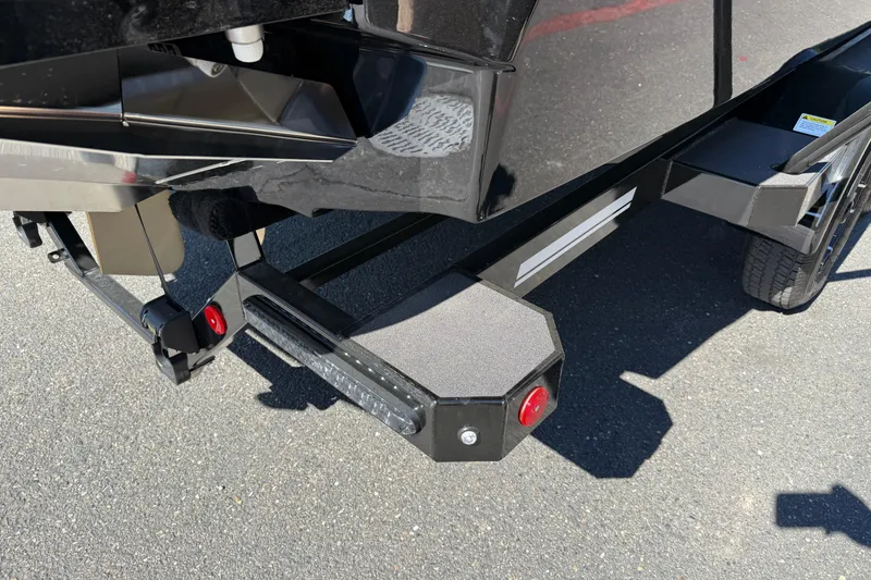 Slide: The Image of 2026 MasterCraft NXT24 boat trailer detail with black finish and red reflector. - 12
