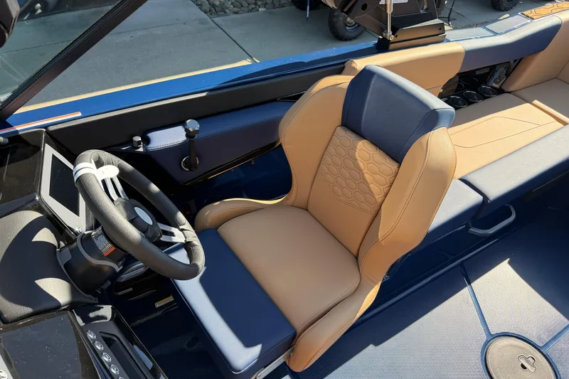 Slide: The Image of 2026 MasterCraft NXT23 boat interior with tan and blue seating, steering wheel, and dashboard. - 15