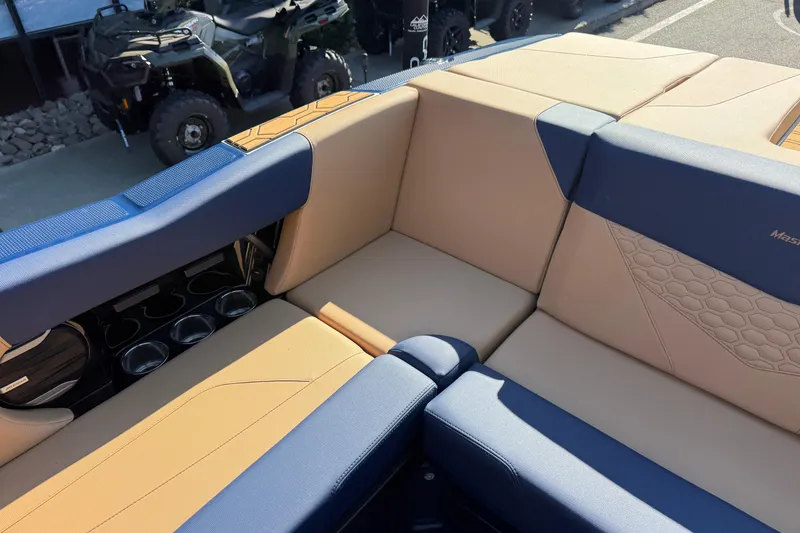 Slide: The Image of 2026 MasterCraft NXT23 boat interior with tan and blue seating, cup holders visible. - 17
