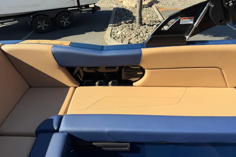 Slide: The Image of 2026 MasterCraft NXT23 boat interior with tan and blue seating, cup holders visible. - 20