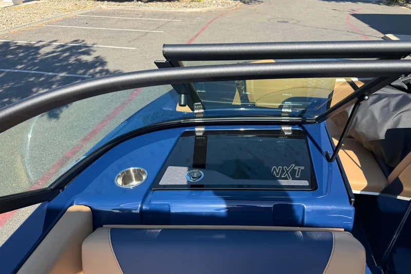 Slide: The Image of 2026 MasterCraft NXT23 boat interior with blue and tan upholstery, windshield, and NXT logo. - 23