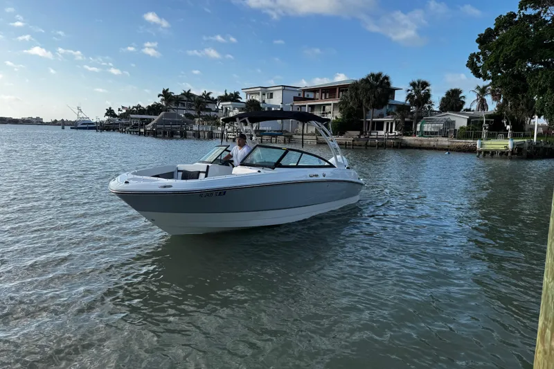 The Image of 2023 Monterey M-225 boat cruising near waterfront homes under a clear blue sky. - 0