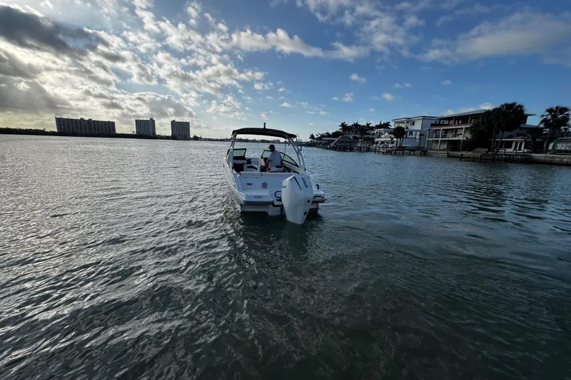 Slide: The Image of 2023 Monterey M-225 boat cruising on a calm waterway near waterfront homes. - 10