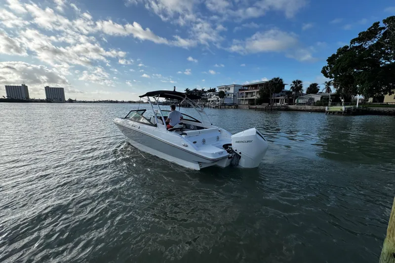 Slide: The Image of 2023 Monterey M-225 boat cruising on a scenic waterway under a partly cloudy sky. - 11
