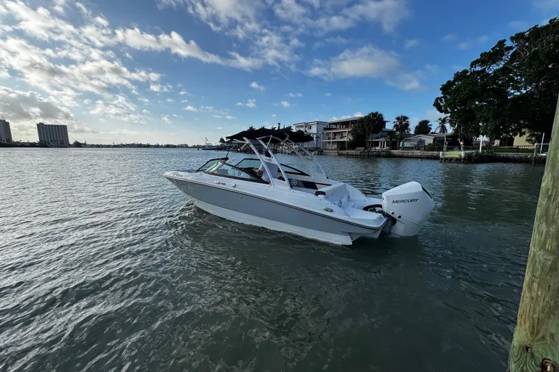 Slide: The Image of 2023 Monterey M-225 boat cruising on a scenic waterway under a partly cloudy sky. - 12