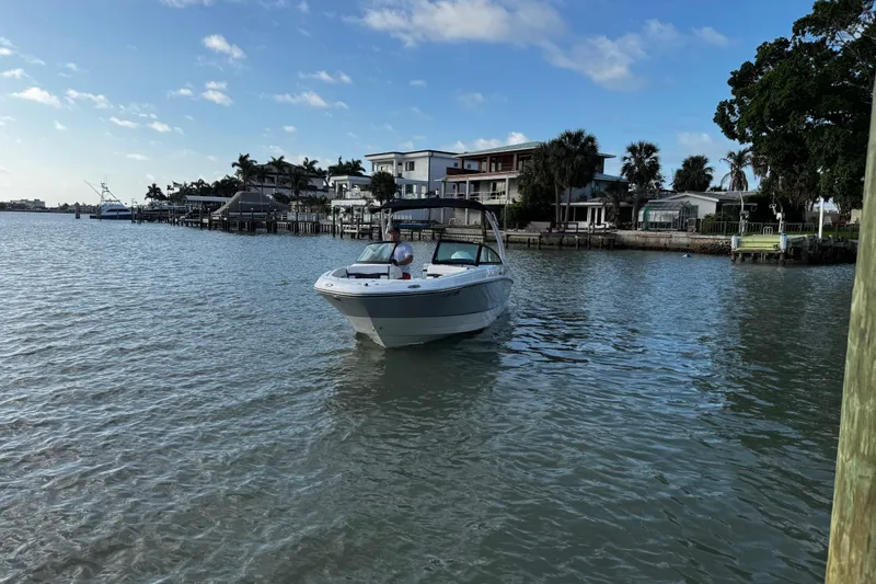 Slide: The Image of 2023 Monterey M-225 boat cruising near waterfront homes under a clear blue sky. - 14