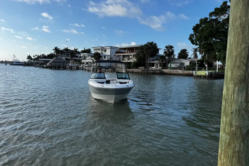 Slide: The Image of 2023 Monterey M-225 boat cruising near waterfront homes under a clear blue sky. - 15