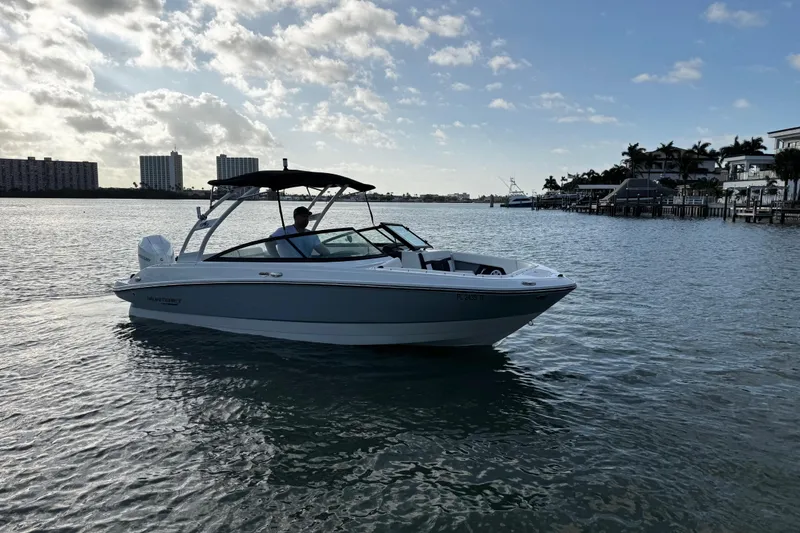 Slide: The Image of 2023 Monterey M-225 boat cruising on a sunny day near waterfront buildings. - 2