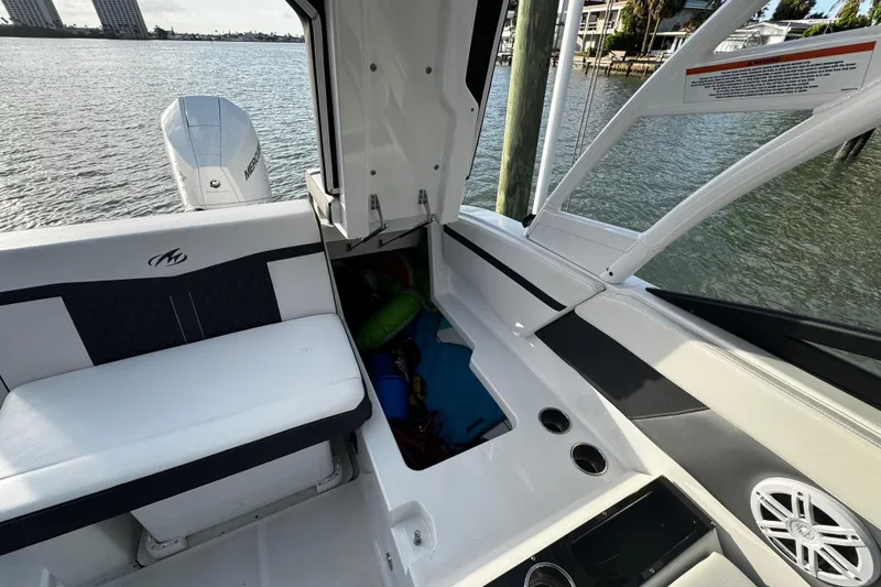 Slide: The Image of 2023 Monterey M-225 boat interior with seating, storage, and water view. - 23
