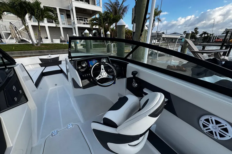 Slide: The Image of 2023 Monterey M-225 boat interior with steering wheel and seating, docked by waterfront. - 25