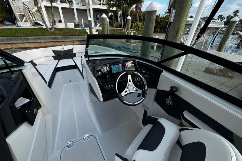 Slide: The Image of 2023 Monterey M-225 boat interior with steering wheel and dashboard, docked by waterfront. - 30