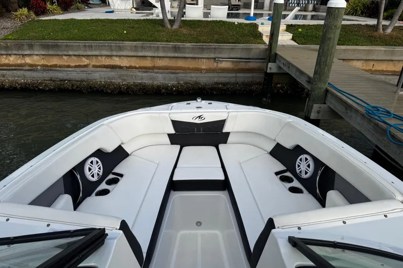 Slide: The Image of 2023 Monterey M-225 boat interior with white seating, cup holders, and speakers docked by a pier. - 35