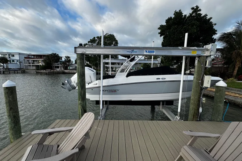 Slide: The Image of 2023 Monterey M-225 boat on lift by waterfront dock with chairs. - 37