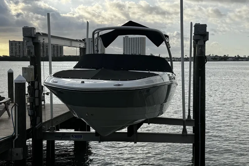 Slide: The Image of 2023 Monterey M-225 boat on lift by waterfront, city skyline in background. - 39