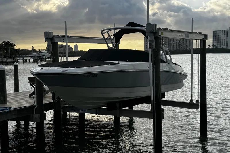 Slide: The Image of 2023 Monterey M-225 boat on lift at marina, with city skyline in background. - 40