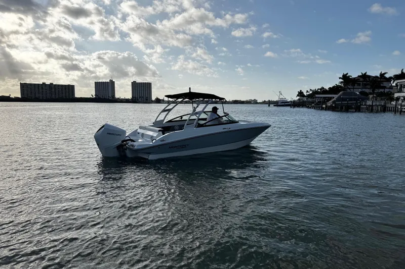 Slide: The Image of 2023 Monterey M-225 boat cruising on a calm waterway under a partly cloudy sky. - 7