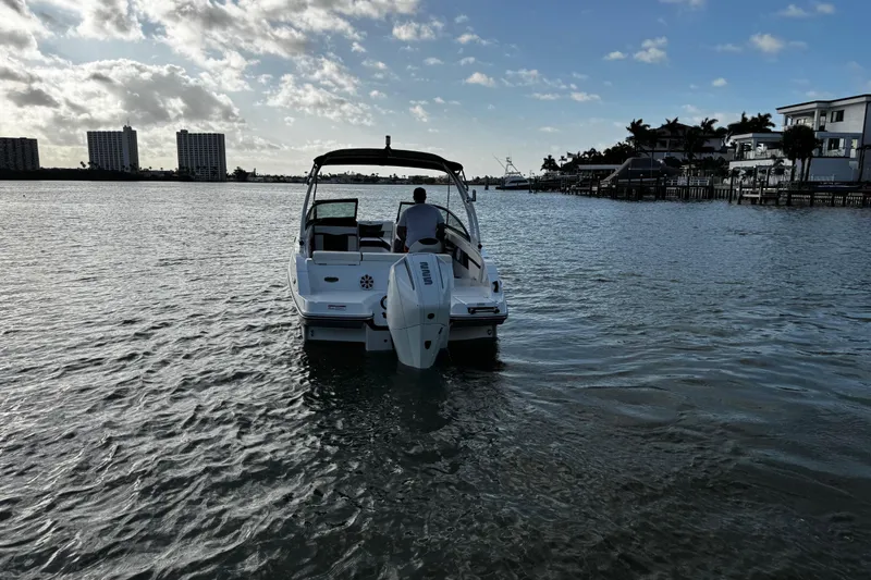 Slide: The Image of 2023 Monterey M-225 boat cruising on a calm waterway with buildings in the background. - 9