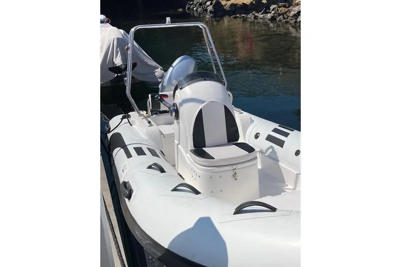 Slide: The Image of White inflatable boat with black accents docked on calm water. - 25