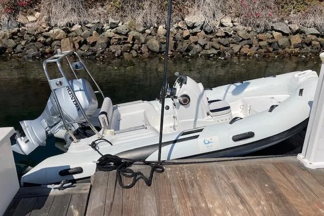 Slide: The Image of A small inflatable boat docked by a wooden pier, featuring a Honda outboard motor. - 28