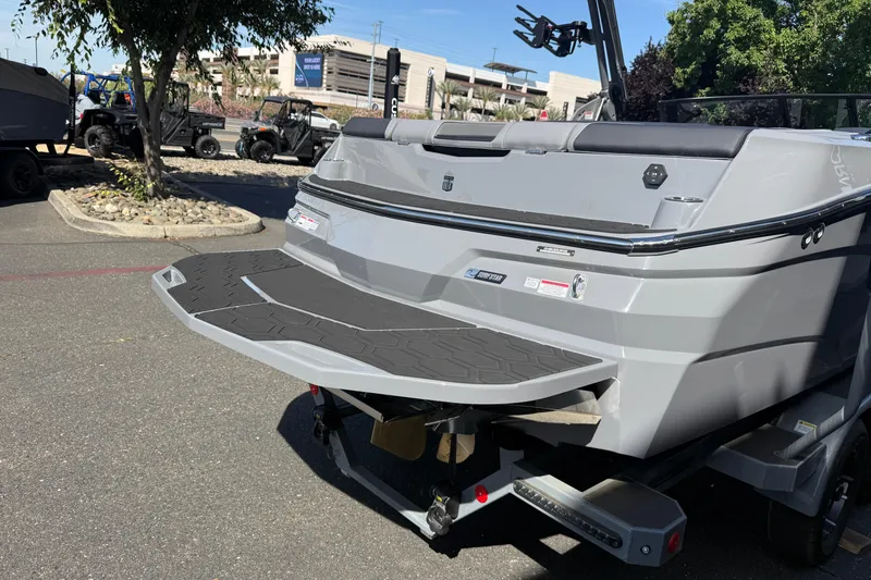 Slide: The Image of 2026 MasterCraft NXT22 boat rear view with swim platform in a parking lot. - 11