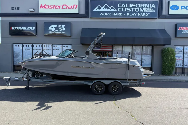 Slide: The Image of Manufacturer Provided Image: 2026 MasterCraft NXT22 boat on water, blue and white design, surrounded by trees. - 31