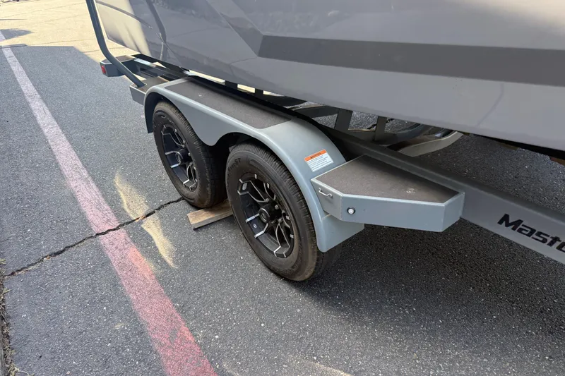 Slide: The Image of Trailer of a 2026 MasterCraft NXT22 boat with dual wheels on asphalt. - 9