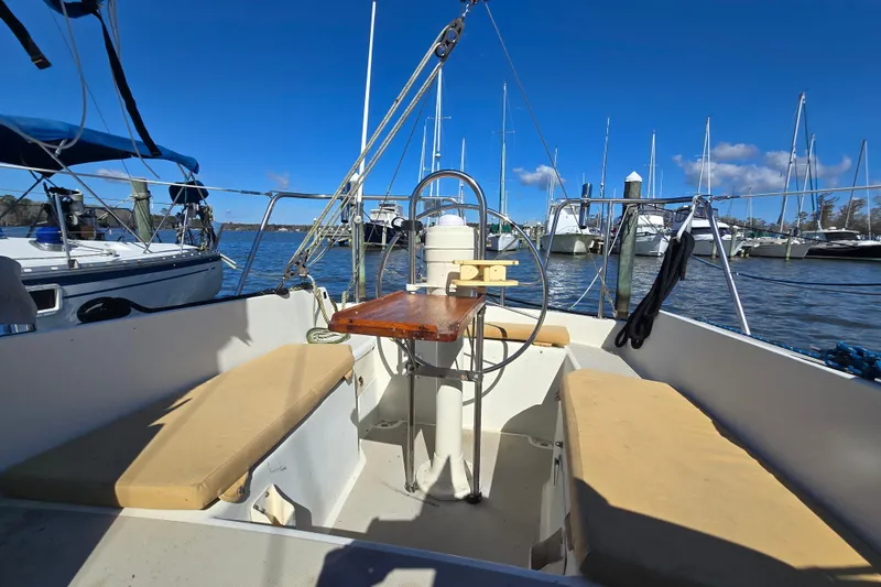 Slide: The Image of 1985 O'Day 31 sailboat cockpit with wooden table, docked in marina under clear blue sky. - 11