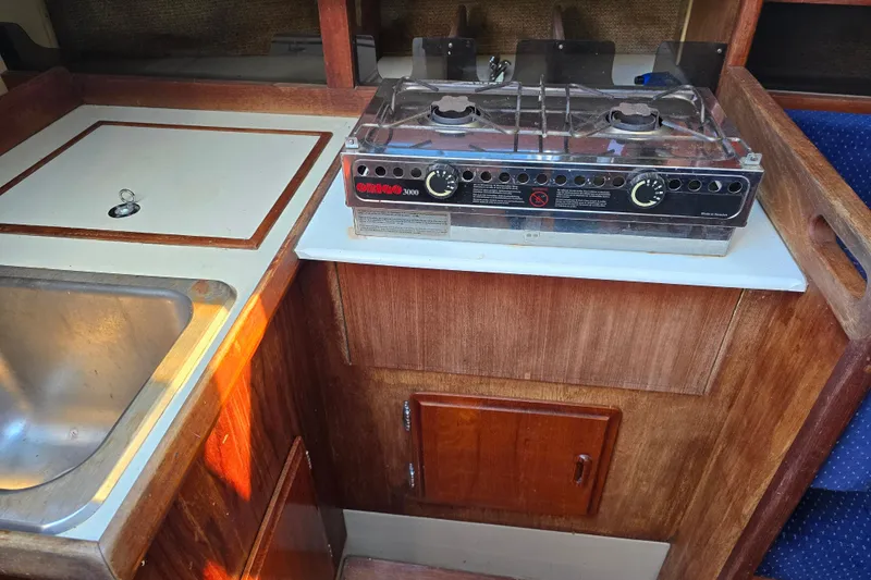 Slide: The Image of 1985 O'Day 31 yacht galley with stove, sink, and wooden cabinetry. - 20