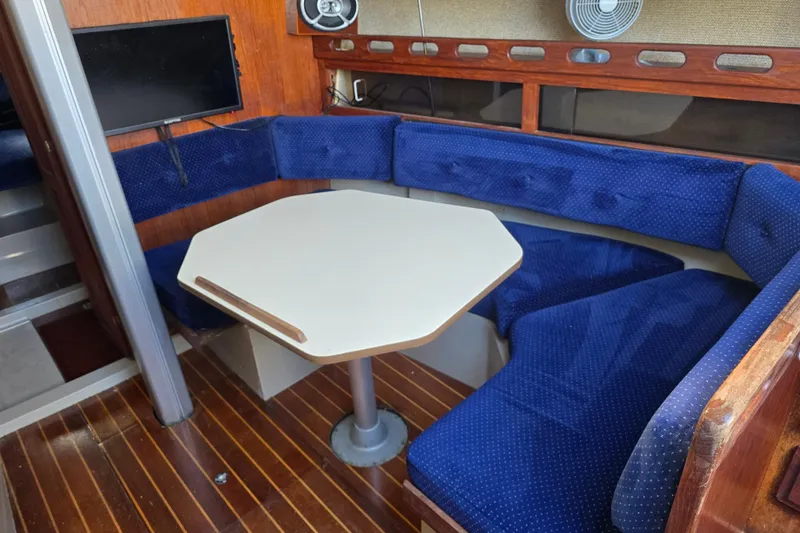 Slide: The Image of Interior of a 1985 O'Day 31 sailboat with blue cushioned seating and a white table. - 22