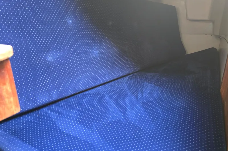 Slide: The Image of Blue cushioned seating inside a 1985 O'Day 31 sailboat cabin. - 28