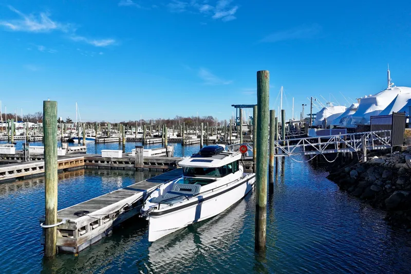 The Image of 2023 Axopar 37 Cross Cabin docked in a marina under a clear blue sky. - 0