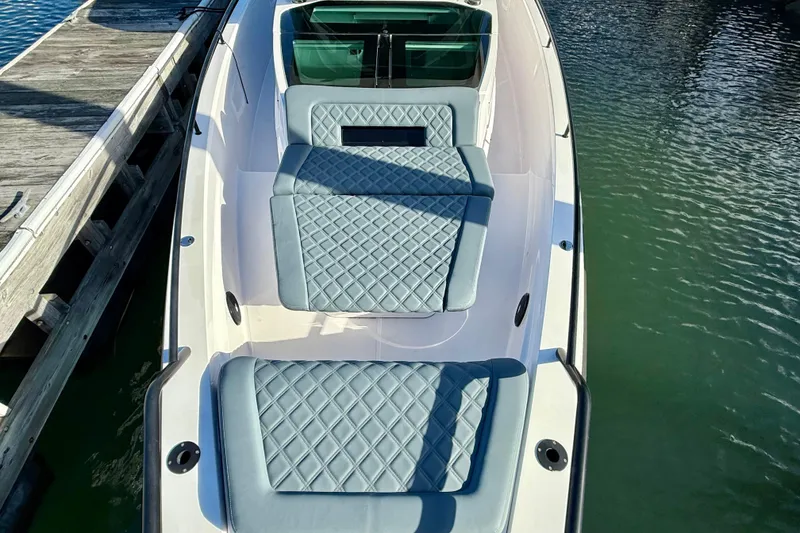 Slide: The Image of 2023 Axopar 37 Cross Cabin boat with quilted seating, docked by the water. - 11