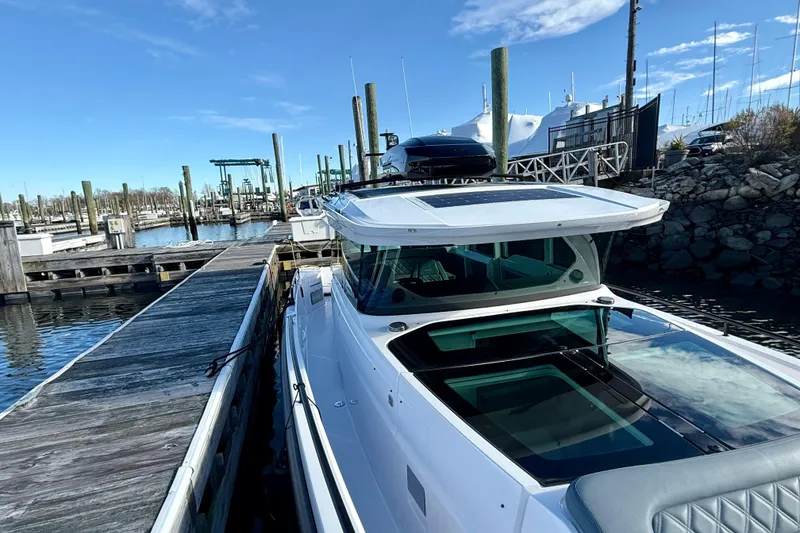 Slide: The Image of 2023 Axopar 37 Cross Cabin docked at a marina under a clear blue sky. - 15