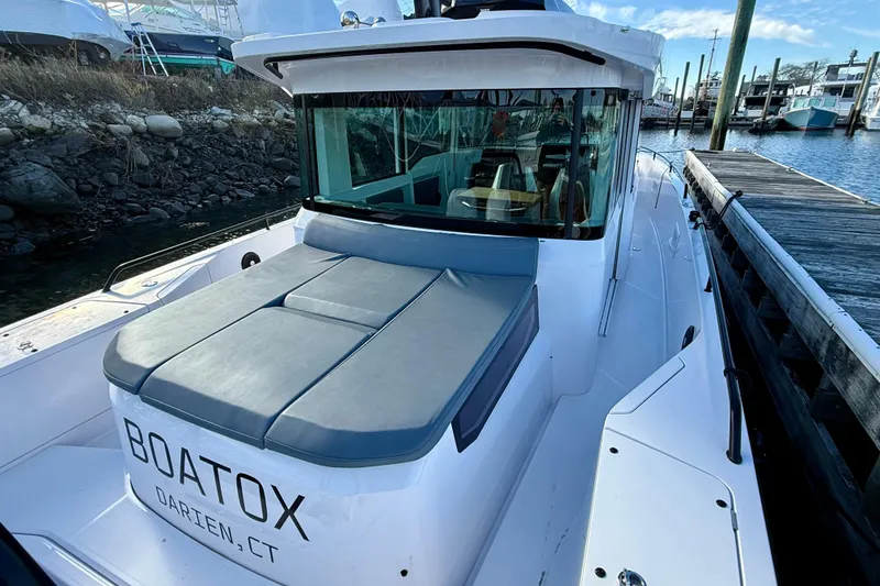 Slide: The Image of 2023 Axopar 37 Cross Cabin boat docked, featuring sleek design and comfortable seating. - 22